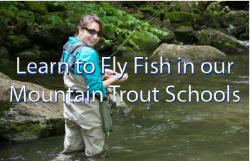 Learn to fly fish for mountain trout in our on the stream schools - Pictured is a young lady standing in a mountain stream with holding a fly rod and a brook trout 